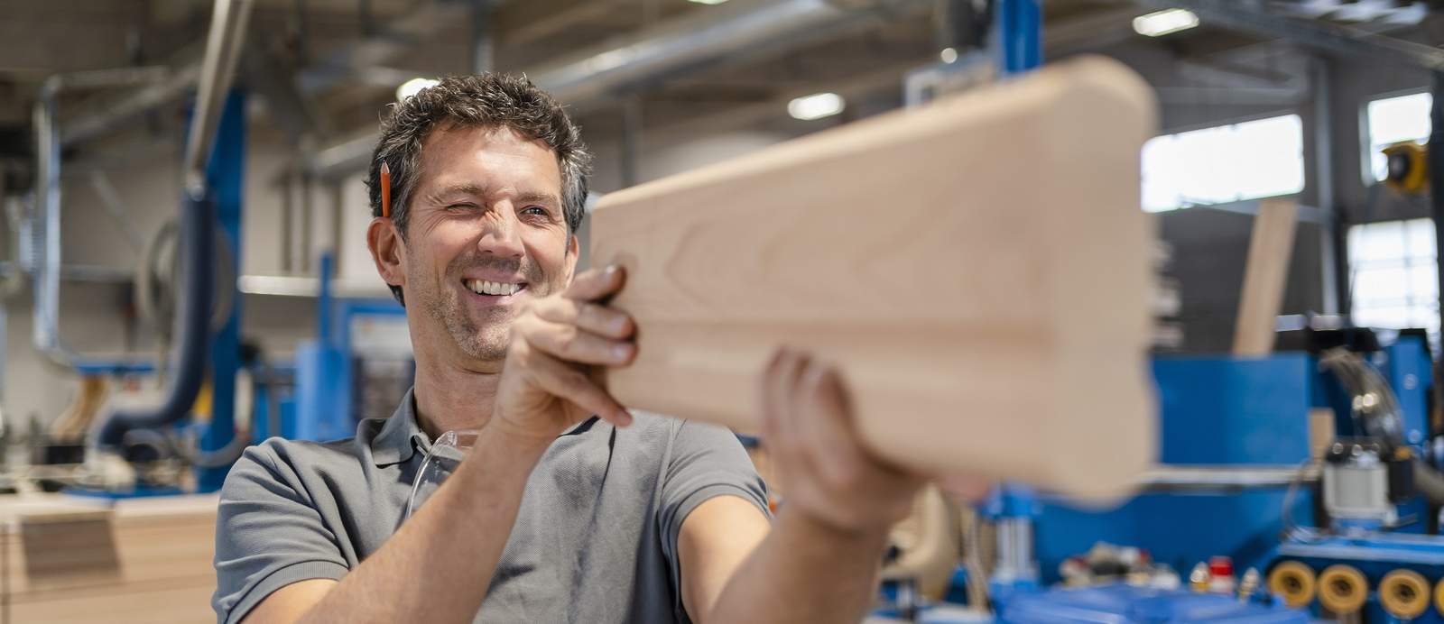 Das Bild zeigt einen Tischler mit einem geschliffenen Holzbrett als Symbol für den Förderschwerpunkt Abfederung negativer Effekte des Übergangs auf eine klimaneutrale Wirtschaft