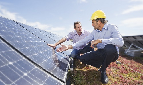 Zwei Monteure in gebückter Haltung vor PV-Panelen auf einem Flachdach, als Beispiel für EU-Förderungen aus dem Fonds für einen gerechten Übergang.