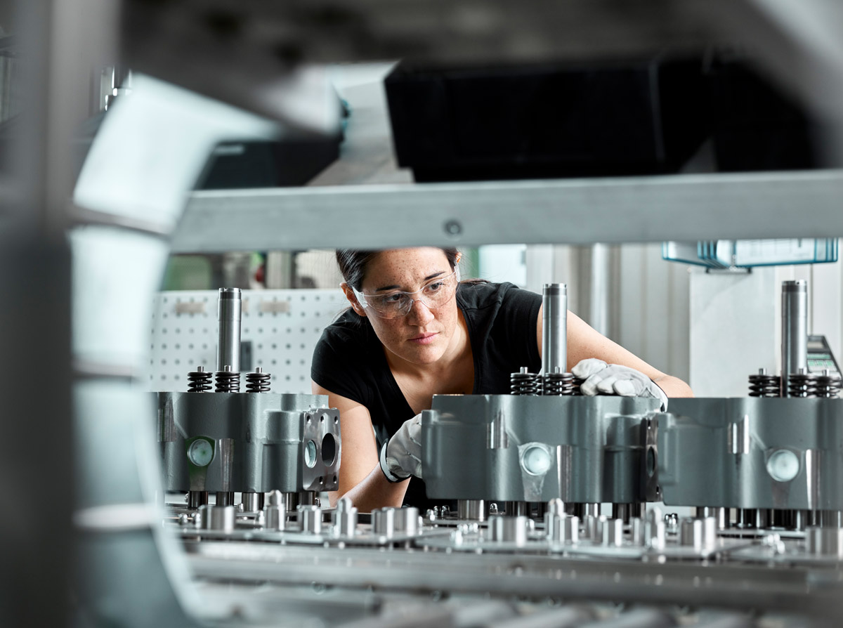 Investitionsförderung in modernste Maschinen ist ein Beispiel für EU-Regionalförderungen aus dem Programm IBW/EFRE & JTF - für Innovation, Wohlstand und Klimaschutz Weibliche Fachkraft kontrolliert Produktionsmaschine, beispielhaft für EU-Förderungen zur Stärkung der regionalen Entwicklung durch Investitionsförderungen in KMU.