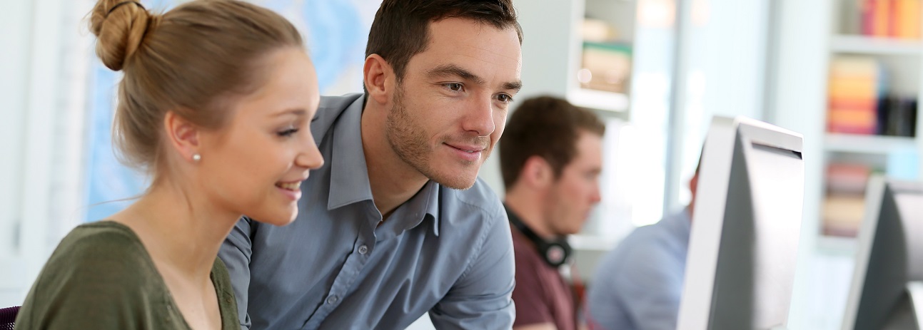 Foto aus einem Großraumbüro mit einer Frau und einem Mann an einem Bildschirm, als Beispiel für mögliche Förderprojekte aus dem Programm.