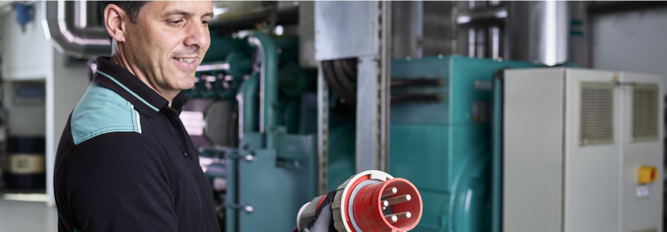 Bild eines Arbeiters der ein Stromkabel aus alternativer Quelle in der Hand hält.