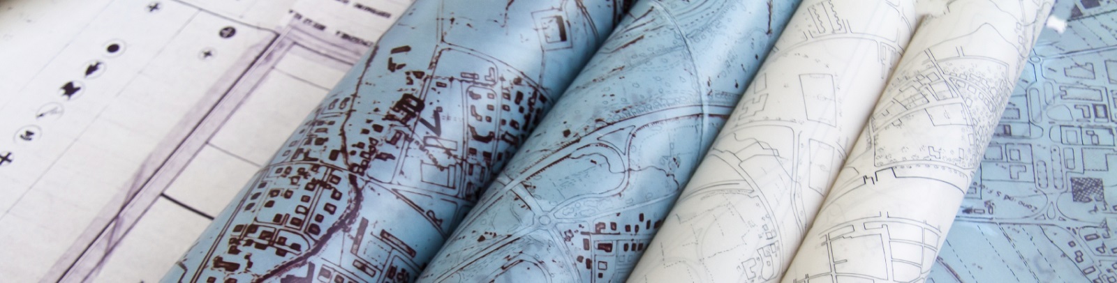 Das Bild zeigt zusammengerollte Stadtpläne als Symbol für den Förderschwerpunkt Verbesserung der Lebensqualität durch Integrierte Territoriale Entwicklung