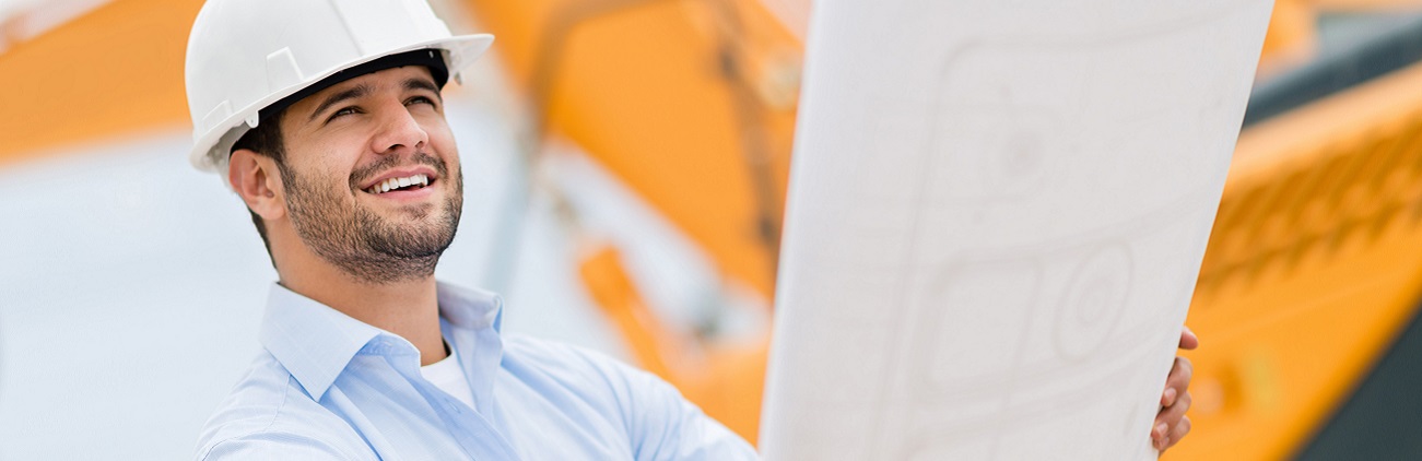 EU-Förderungen für KMU sind im Förderprogramm IWB/EFRE auch für Bauprojekte möglich. Architekt auf einer Baustelle mit einem Plan in beiden Händen.